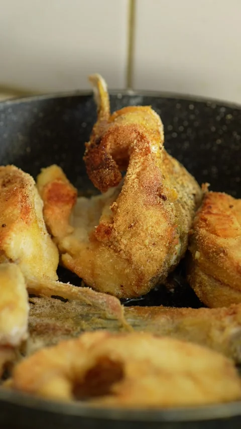 Fried fish steaks and a tail portion cooking in a black frying pan. Stock Footage 344784134