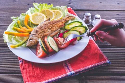 Fried fish with vegetables on a tablecloth, fried on nature Stock Photos