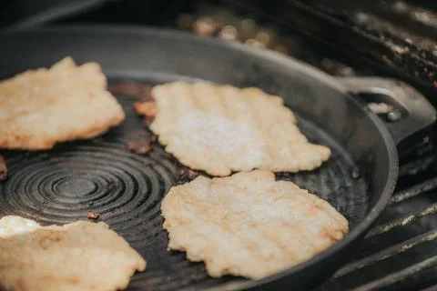 Fried flatbreads cooking in a cast iron skillet on a grill, with a textured.. Stock Photos