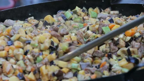 Fried fresh meat with potatoes and vegetables on a big round pan in outdoor cafe Stockbeeldmateriaal 132693411
