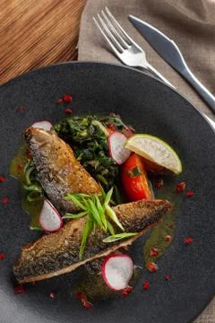 Fried mackerel fish with vegetable garnish: spinach in coconut milk, radish,  Stock-Fotos