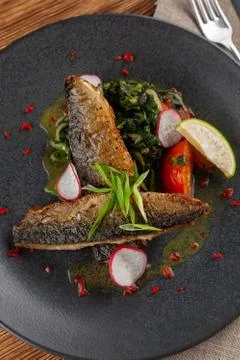 Fried mackerel fish with vegetable garnish: spinach in coconut milk, radish,  Stock-Fotos