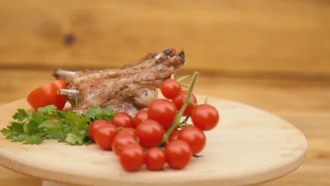 Fried meat and tomatoes spin on a wooden tray Stock Footage 117030457