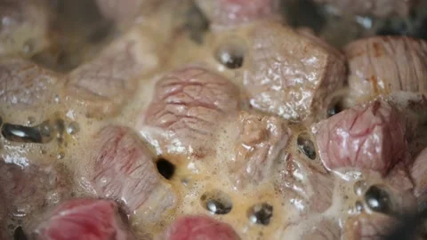 Fried meat in chunks in oil in a hot black pan. Preparing minced meat Stock Footage 143992198