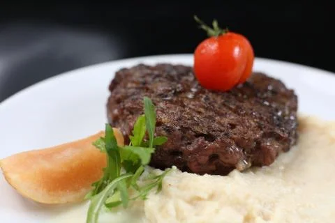 Fried meat cutlet on a plate, with celery puree, garnished with tomato cherry Stock Photos