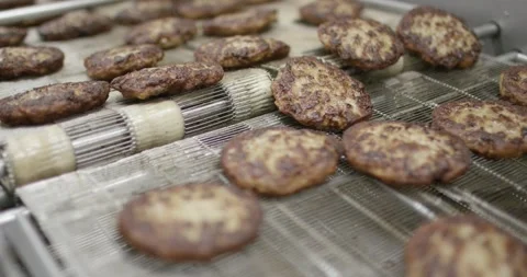 Fried meatballs moving on wire conveyor through cooking line, Slow Motion Stock Footage 340044027