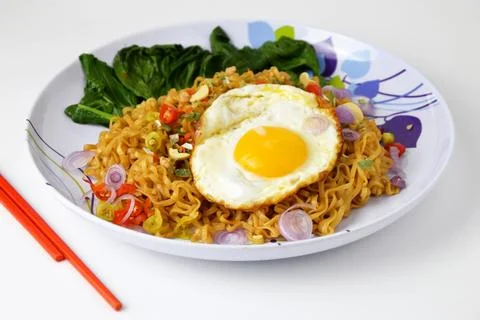 Fried noodles with sunny side up egg and mixed vegetables on a plate Stock Photos
