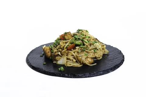 Fried noodles with vegetables and meat in a flat plate on a white background Stock Photos