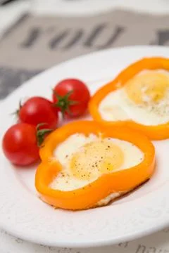Fried organic eggs inside orange paprica rings. Eggs served with tomatos and  Stock Photos