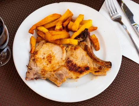 Fried pork chops with bone, supplemented with slices of French fries Stock Photos