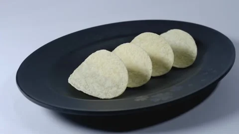 Fried potato snacks thinly sliced on a black plate Stock Footage 240602119
