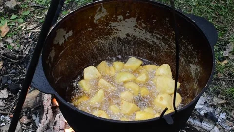Fried potatoes are cooking in cauldron over an open fire Stock Footage 154212295