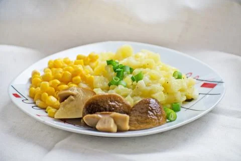 Fried potatoes with cepes and corn in a plate on the table. Fried potatoes wi Stock Photos