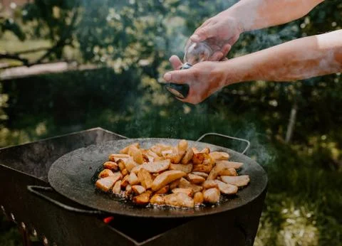 Fried potatoes with a crust cooked in a large black pan on the grill Stock Photos