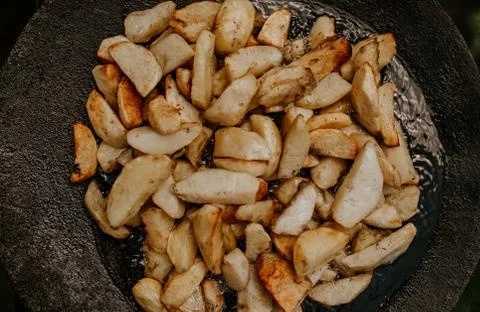 Fried potatoes with a crust cooked in a large black pan on the grill Stock Photos