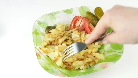 Fried potatoes in green plate.Sticks a fork into a cucumber. Vídeos de archivo 136741089