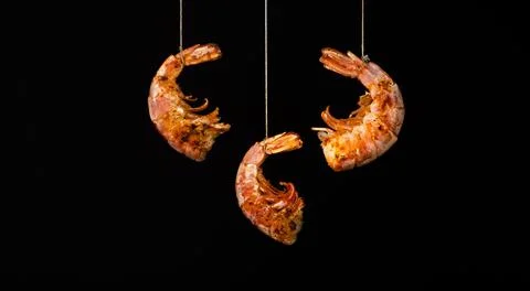 Fried prawn hang on strings on a black background Stock Photos