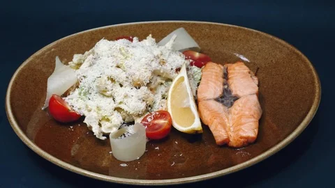Fried red fish and lettuce sprinkled with parmesan with a slice of lemon in a Stock Footage 99223780