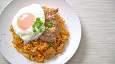 Fried rice cake with fried egg and vegetables on a white plate Stock Photos