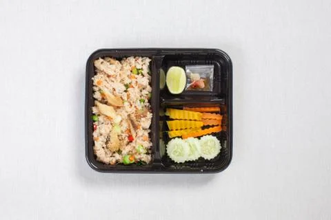 Fried rice with fried fish put in black plastic box, put on a white tableclot Stock Photos