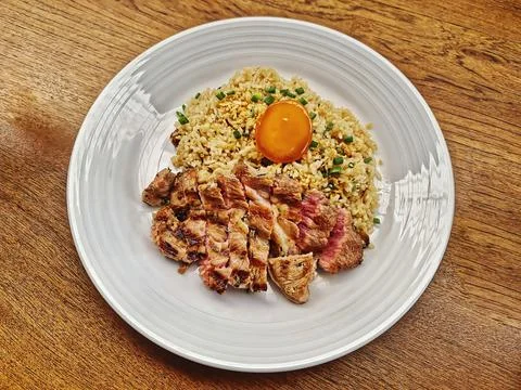 Fried Rice with Medium Rare Beef Steak and Egg on Wooden Table Foto stock