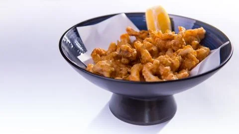 Fried ring octopus with lemon in blue chinese bowl on white background Stock Photos