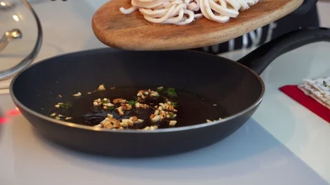 Fried rings of squid with herbs and onion in the frying pan. Видео 102209835