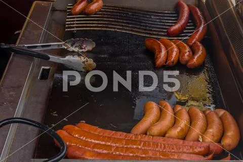 Fried sausages in big frying pan at a seasonal fair. Stock Photos