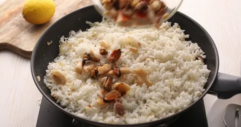 Fried seafood is added to the rice pan. Stock Footage 249525656