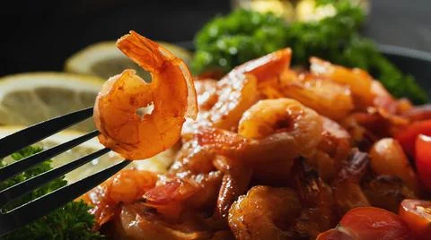 Fried shrimp on a fork close-up on a background of shrimp and greens on a pla Stock Photos