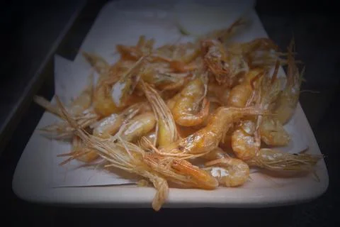 Fried shrimp with salt on a plate on the table in a restaurant Stock Illustration