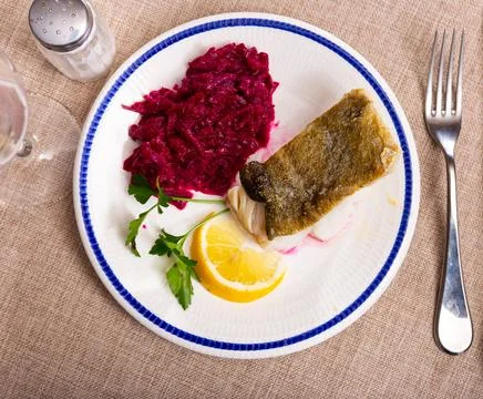Fried slice of cod fillet served with stewed beetroot. Stock Photos