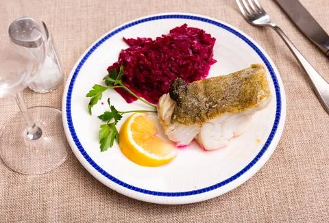 Fried slice of cod fillet served with stewed beetroot. Stock Photos