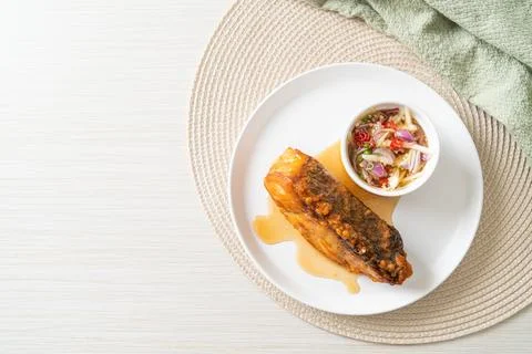 Fried snapper fish with fish sauce and spicy salad Stock Photos