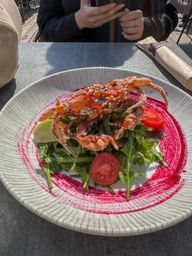 Fried soft-shell crab salad on a plate, at the outdoor beach restaurant. Stock Photos