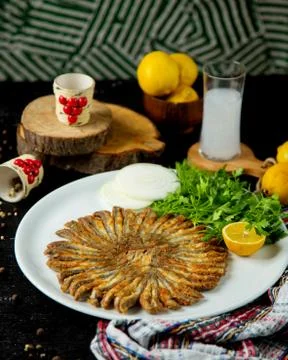 Fried sprats in round shape served with parsley and lemon Stock Photos