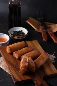 Fried spring rolls with dipping sauce on a wooden cutting board Foto stock