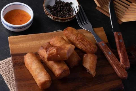 Fried spring rolls with dipping sauce on a wooden cutting board Stock Photos