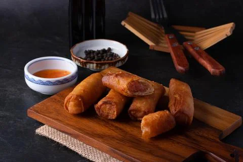 Fried spring rolls with dipping sauce on a wooden cutting board Stock Photos