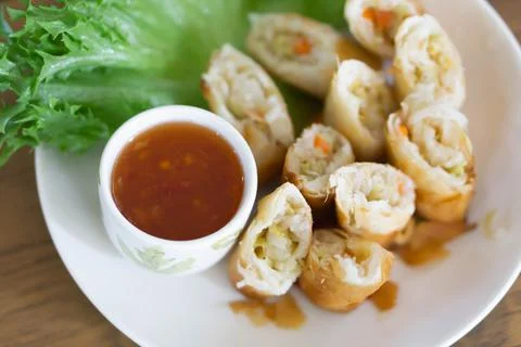 Fried spring rolls with fresh vegetables are placed in the plate on the dinin Stock Photos