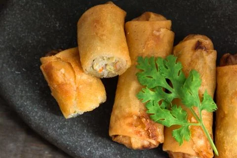 Fried Spring Rolls Stacked on black slate plate on wooden.top view Stock Photos