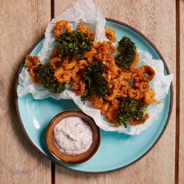 Fried squid with crispy kale and sumac mayo, overhead view Stock Photos