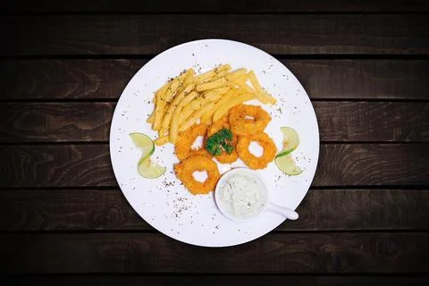 Fried squid or octopus (squid) in tartar sauce served with french fries and.. Stock Photos