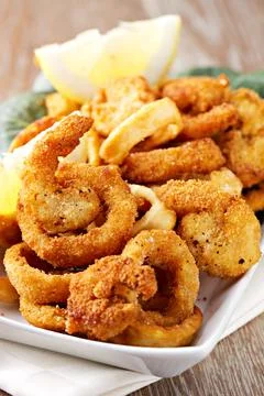 Fried squid rings breaded with lemon on a plate Stock Photos