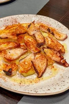 Fried squid served on top of crispy potato wedges Stock Photos