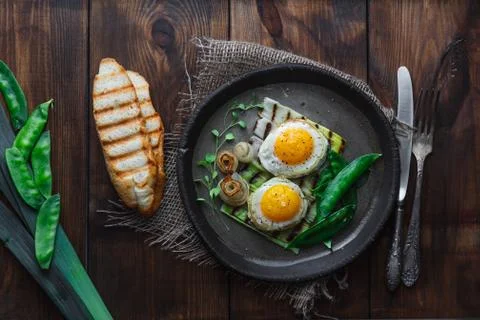 Fried sunny side egg with onion and snow peas, breakfast concept, dark photo Stock Photos