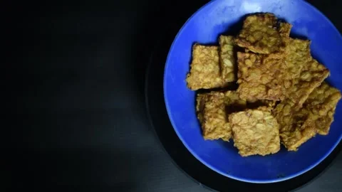 Fried tempeh slices served on a blue plate Stock Footage 313983669