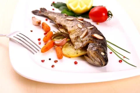 Fried trout with vegetables and split almonds Stock Photos