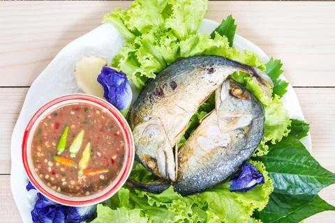 Fried two mackerels with vegetable on white on wooden table Stock Photos
