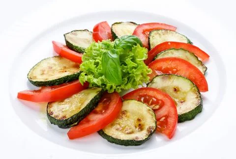 Fried vegetable marrows with greenery and tomatoes. Stock Photos